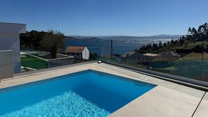 A swimming pool with a clear view of the sea and distant mountains.