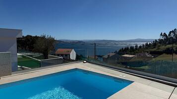 A swimming pool with a clear view of the sea and distant mountains.
