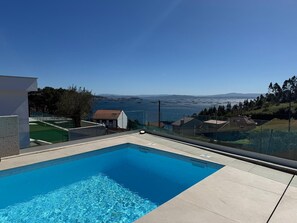 Una piscina con vistas despejadas al mar y montañas a lo lejos.