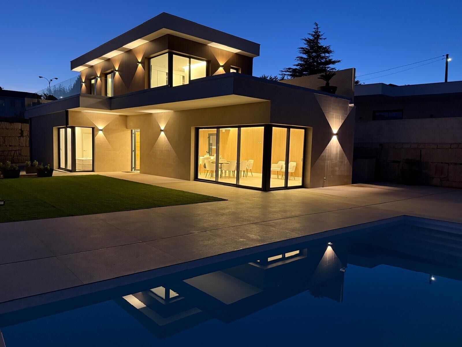 A modern two-story house with a swimming pool in the foreground.