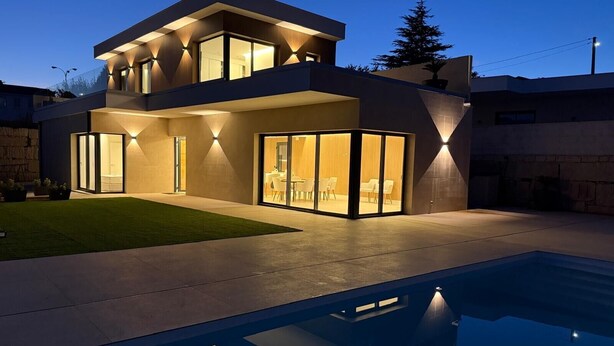 A modern two-story house with a swimming pool in the foreground.