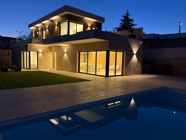 Una casa moderna de dos pisos con una piscina al frente.