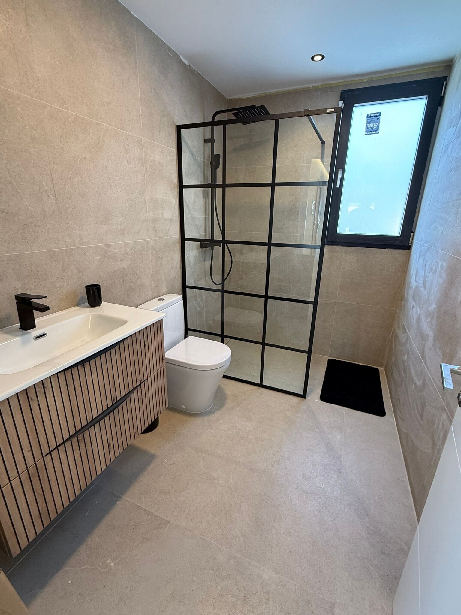 A modern bathroom with a shower enclosure, a toilet, and a sink.