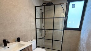 A modern bathroom with a shower enclosure, a toilet, and a sink.