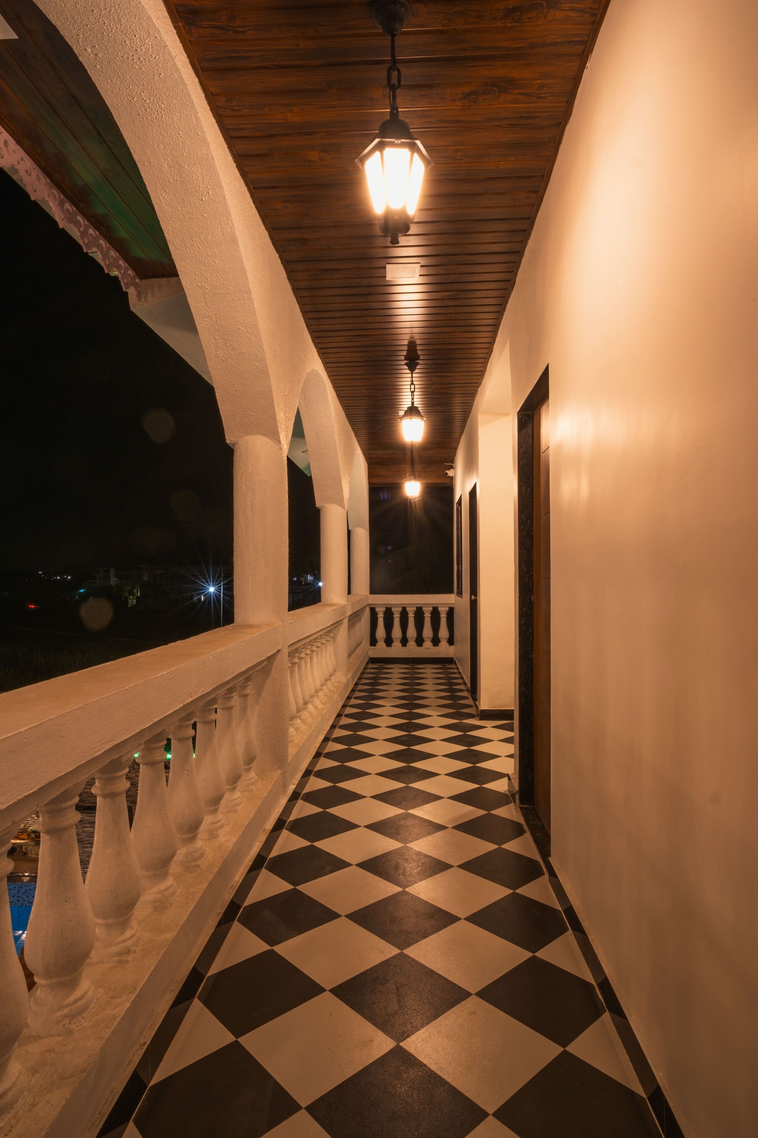 A corridor with a checkered floor, white walls, and a wooden ceiling.