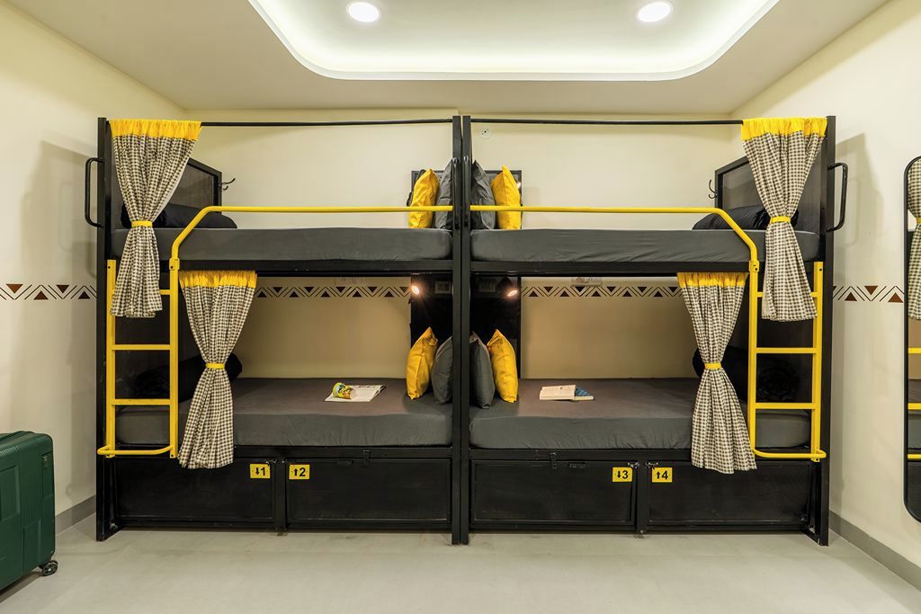 A bunk bed room with two beds, each with a ladder, and a small table in the center.