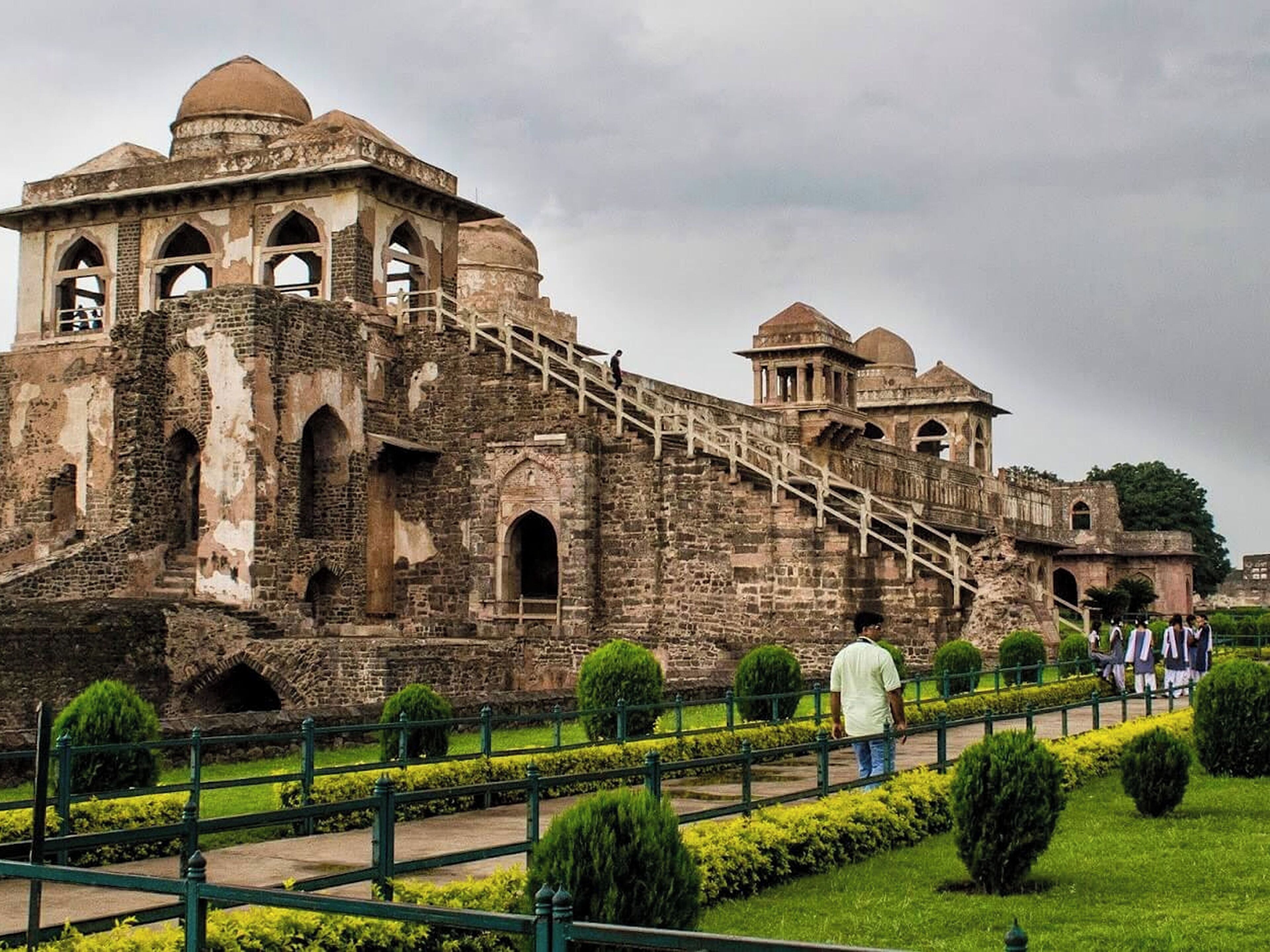 A historic building with a large staircase leading to a dome, surrounded by well-maintained gardens.