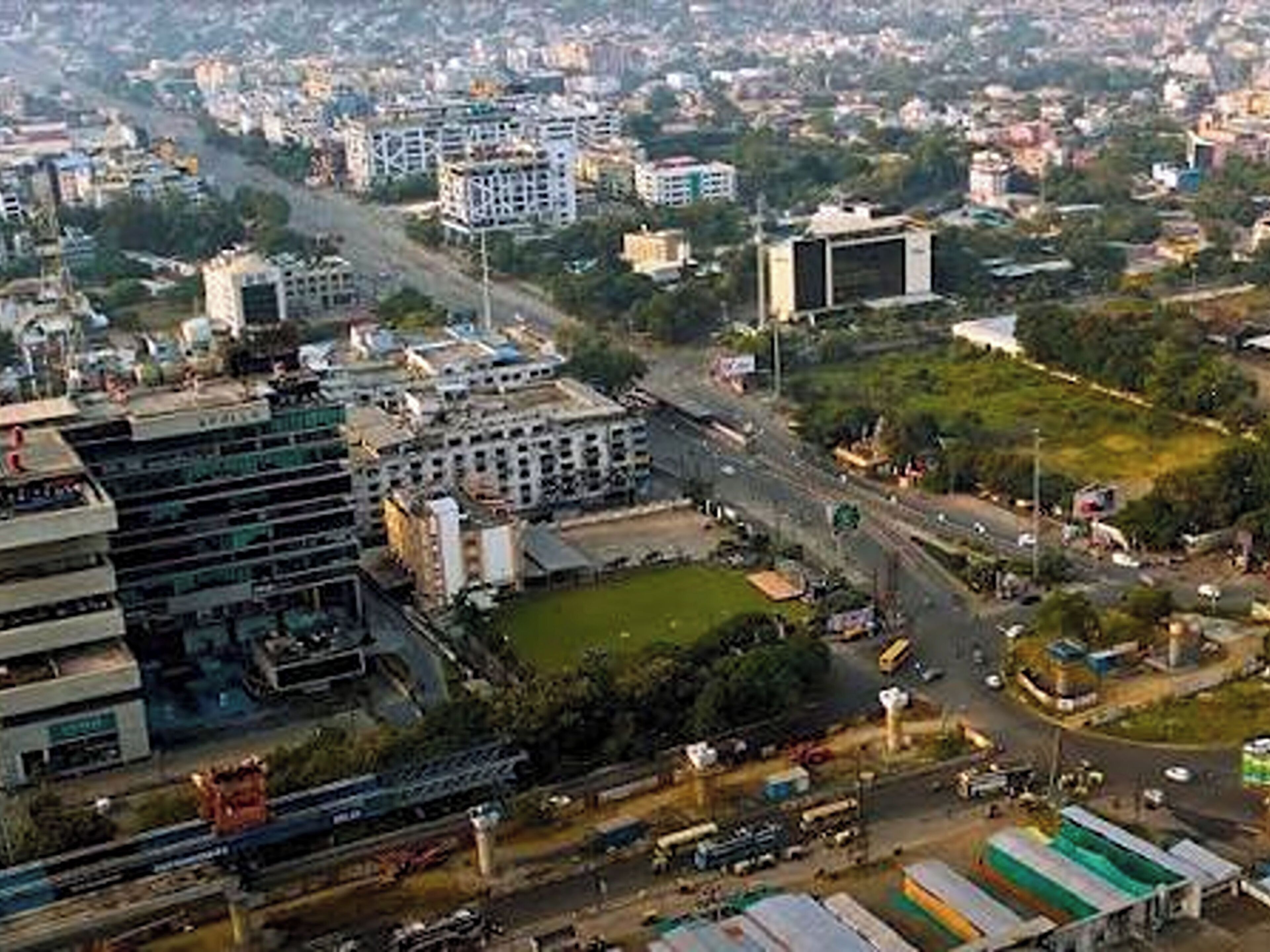 A cityscape with a mix of residential and commercial buildings, roads, and greenery.