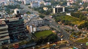 Paisagem urbana com edifícios residenciais e comerciais, ruas e áreas verdes.