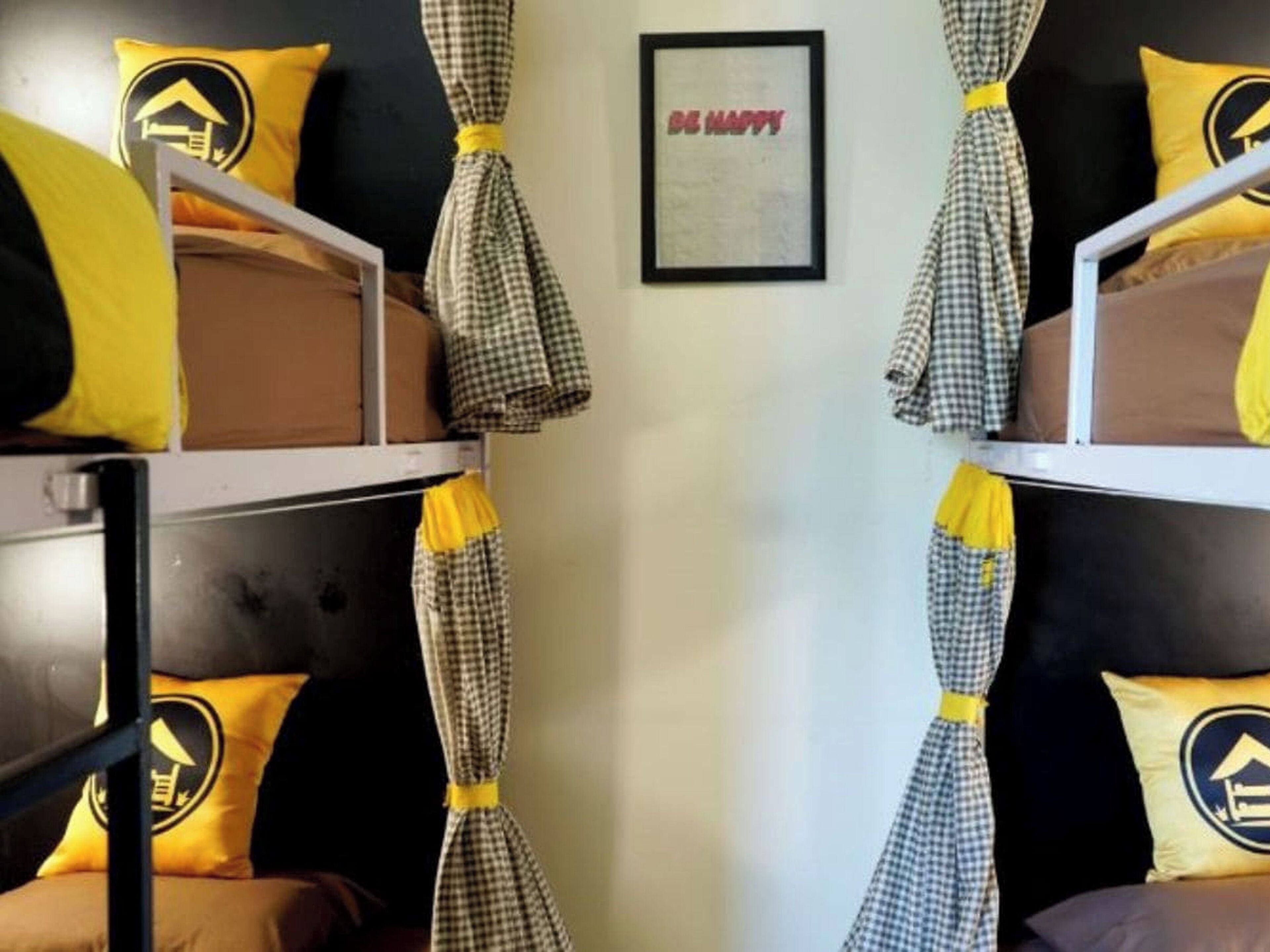 A bunk bed room with checkered curtains and yellow pillows with a house logo.