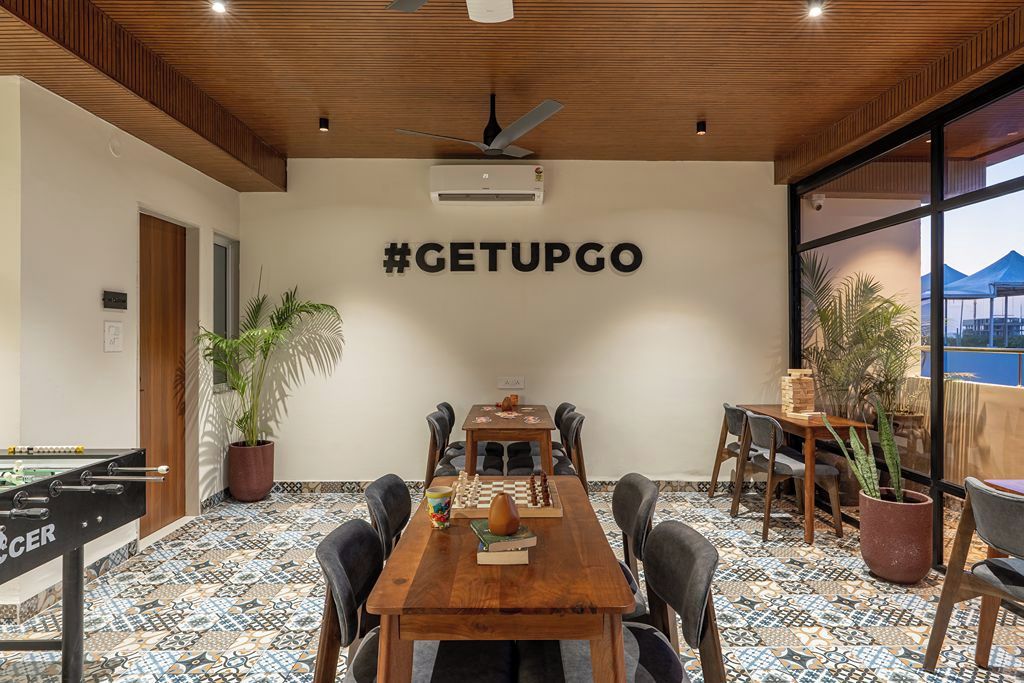 A conference room with a wooden table, chairs, a foosball table, a chessboard, and a wall-mounted air conditioning unit.