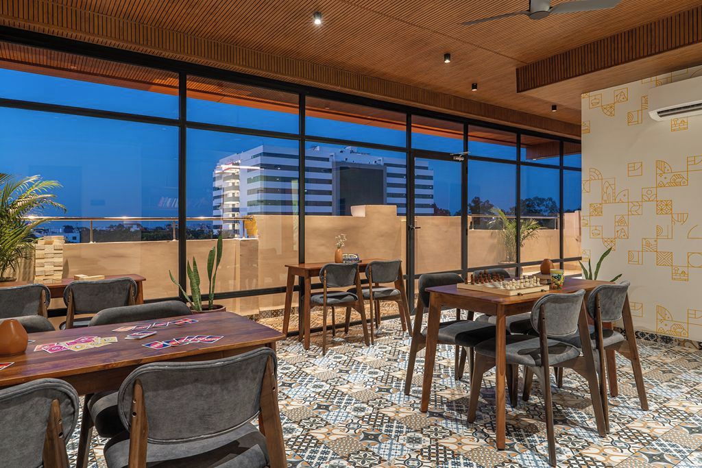 Un espacio interior moderno con ventanas amplias, techo de madera y baldosas de suelo con diseño.
