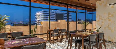 A modern indoor space with large windows, wooden ceiling, and patterned floor tiles.