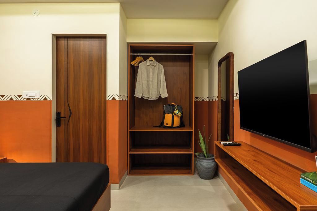 A hotel room with a bed, a wardrobe, a television, and a potted plant.