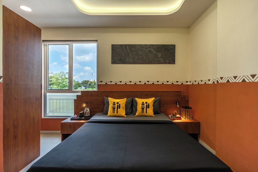 Un dormitorio moderno con una cama grande, dos mesitas de noche, una mesita auxiliar, un ventanal con vistas y un panel de pared de mármol.