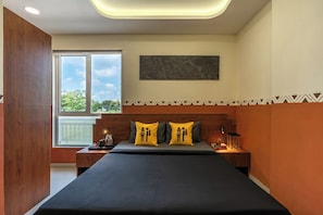 A modern bedroom with a large bed, two bedside tables, a nightstand, a window with a view, and a marble wall piece. - The Hosteller Indore (Indore)
