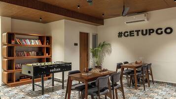 A room with a foosball table, a bookshelf, a chess table, and a wall with a hashtag sign.