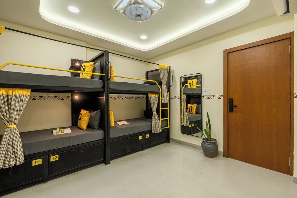 Een slaapkamer met stapelbed, een spiegel, een potplant en een houten deur.