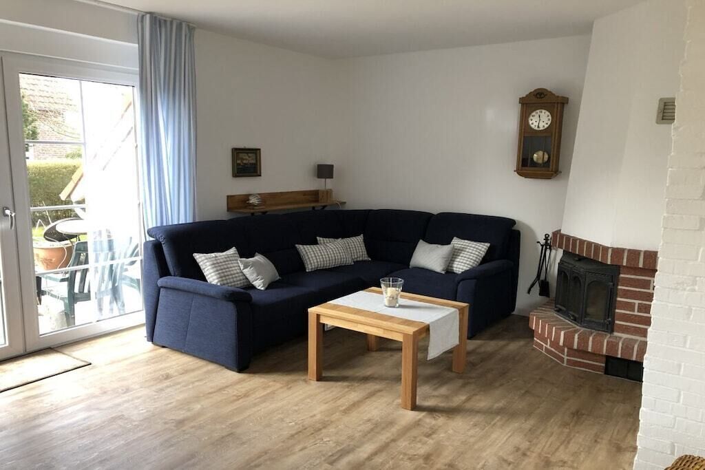 A living room with a dark blue sofa, a wooden coffee table, a fireplace, and a clock on the wall.