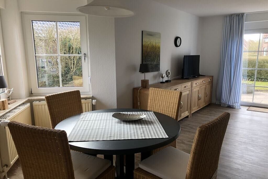 A dining area with a round table, chairs, a cabinet, and a television.