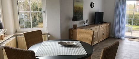 Un coin repas comprenant une table ronde, des chaises, un buffet et un téléviseur.