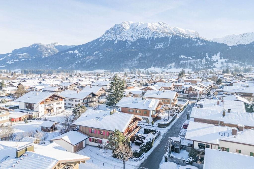 Une ville enneigée, avec des bâtiments et une montagne en arrière-plan.