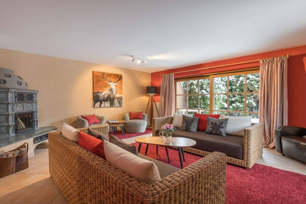 A cozy living room with wicker furniture, a fireplace, and a large window with curtains.