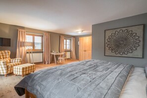 A bedroom with a bed, a chair, a table, and a wall-mounted artwork. - Holiday home with 4 bedrooms (Oberstdorf)