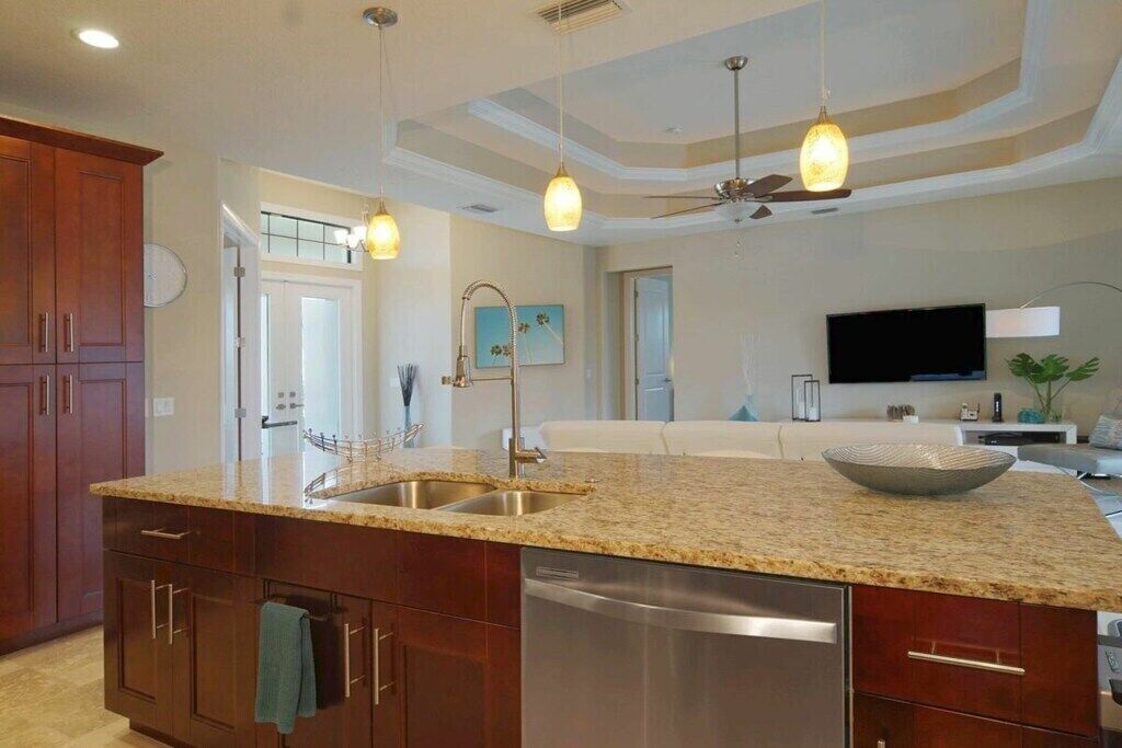 A modern kitchen with granite countertops, stainless steel appliances, and pendant lighting.