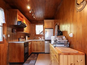 A compact kitchen with wooden cabinets, a built-in oven, a refrigerator, and a coffee machine. - Carpe Diem Appartement/Fewo, Dusche und Bad, WC 3 1/2 Zimmerwohnung, 6-Betten by Interhome (Riederalp)
