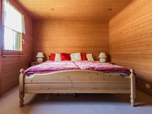 A wooden-paneled room with a bed, two bedside lamps, and a window with a curtain. - Carpe Diem Appartement/Fewo, Dusche und Bad, WC 3 1/2 Zimmerwohnung, 6-Betten by Interhome (Riederalp)