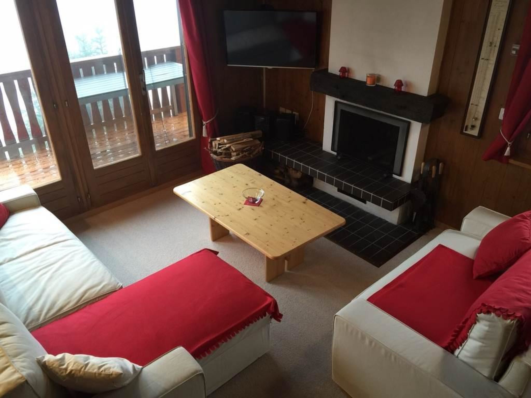 Ein gemütliches Wohnzimmer mit Kamin, Fernseher und Balkonblick.