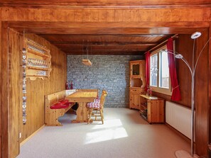 Ein Holzinterieur mit einer Steinwand, einem Holztisch mit Bänken und einem roten Vorhang.