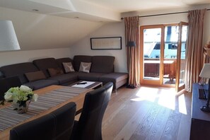 Ein modernes Wohnzimmer mit einer Eckcouch, einem Holztisch und einem Essbereich mit Stühlen.