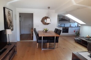Un espacio habitable moderno con comedor, cocina y habitación doble en entrepiso con tragaluz.