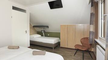 A bedroom with a bed, a chair, a wardrobe, and a television.