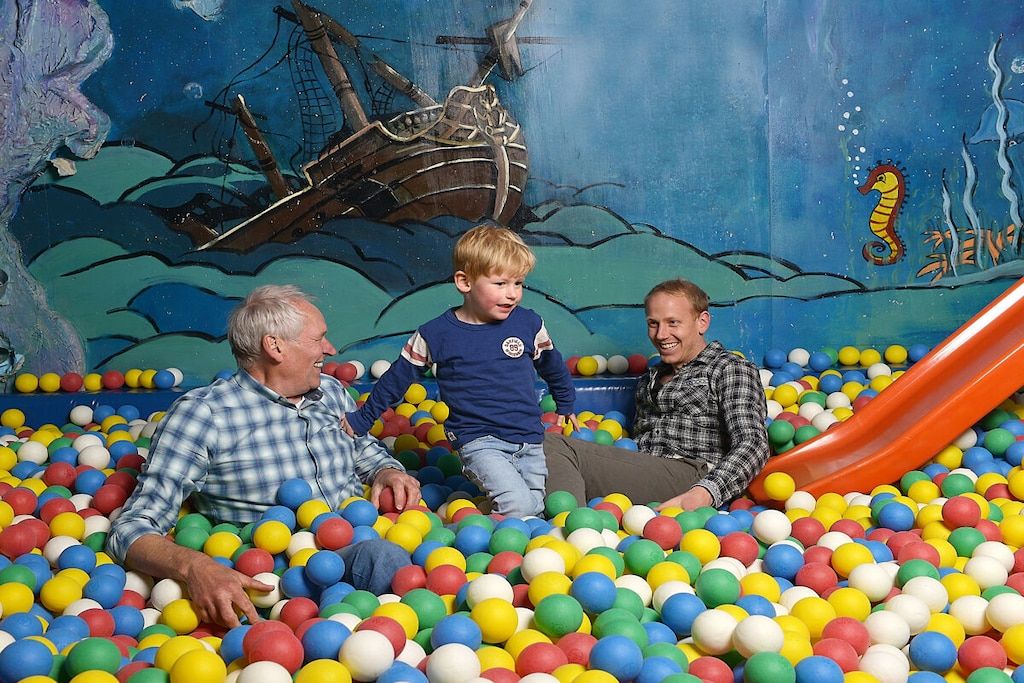 A ball pit with a mural of a shipwreck and a seahorse.