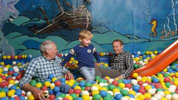 A ball pit with a mural of a shipwreck and a seahorse.