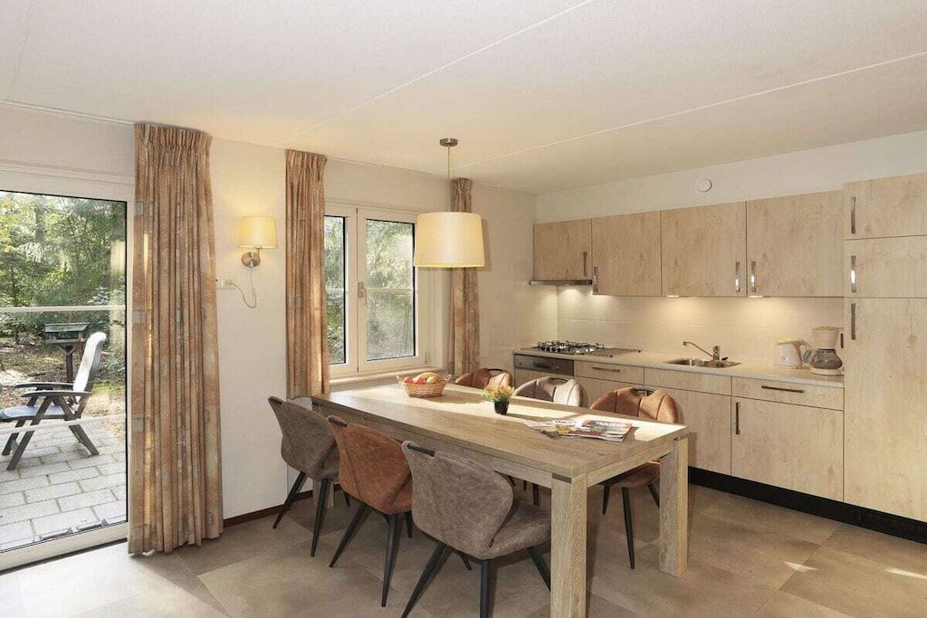 A modern kitchen with a central island, dining chairs, and a view of the outdoors.