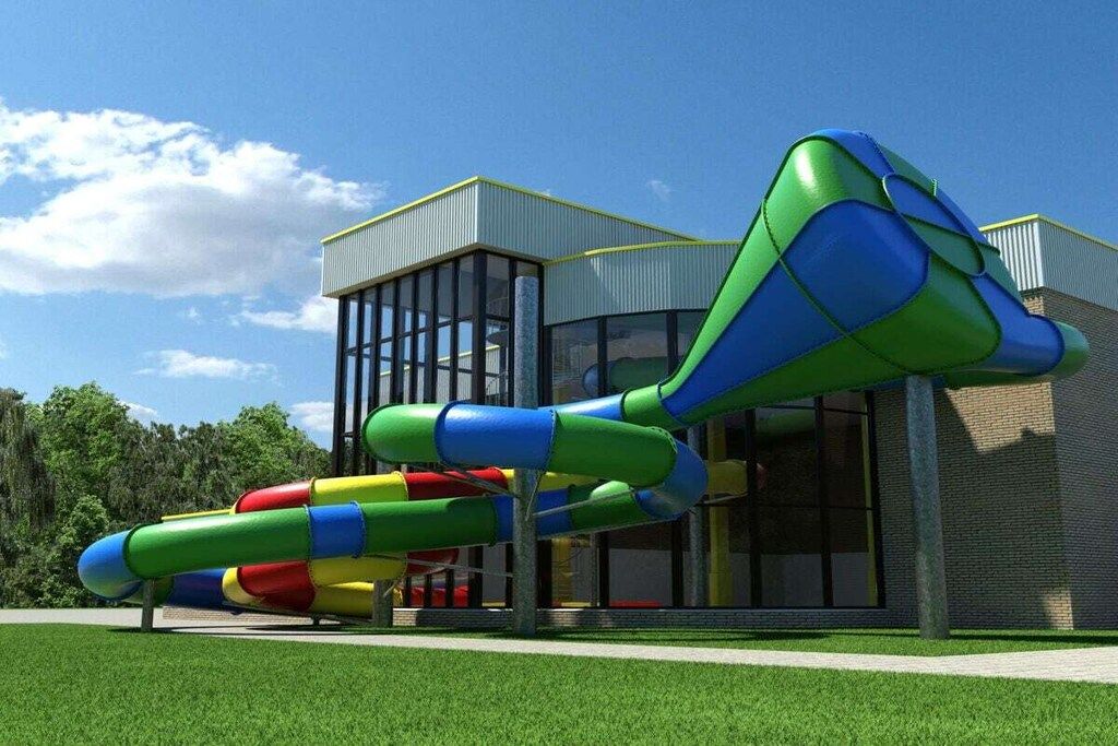 A playground with a slide and a climbing structure in front of a building with large windows.