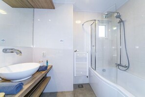 A modern bathroom with a white sink, wooden vanity, and a glass-enclosed shower. - Comfort, 2 bathrooms (DEURNINGEN)
