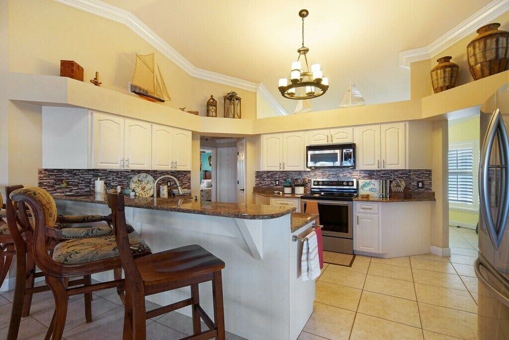 A kitchen with a central island, white cabinetry, a microwave, and a refrigerator.