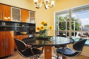 Une cuisine avec des meubles en bois, un plan de travail noir et une table en verre avec des chaises.