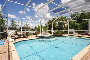 Une piscine intérieure dotée d’un toit en verre, de chaises longues et de statues décoratives.