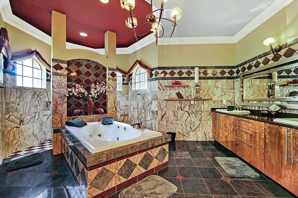 A spacious bathroom with a large bathtub, marble walls, and a modern vanity.