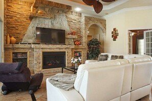 Un salon avec une cheminée en pierre, un téléviseur à écran plat, un canapé et une table basse.