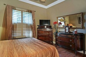 Une chambre à coucher avec un lit, une commode, un téléviseur et un miroir.