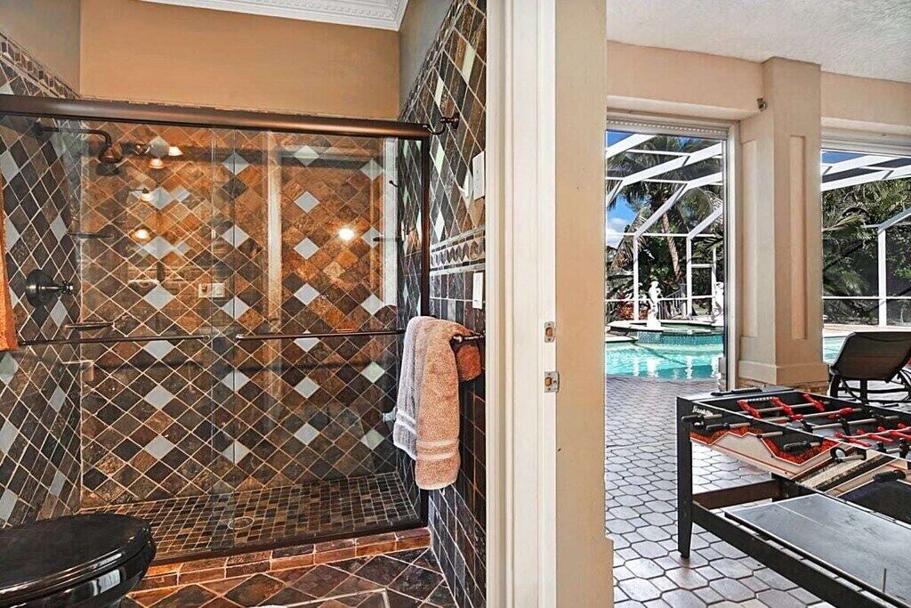 A bathroom with a shower, a toilet, and a glass-enclosed area with a patterned tile wall.