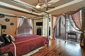 Une chambre à coucher avec un grand lit, un ventilateur de plafond et un téléviseur.