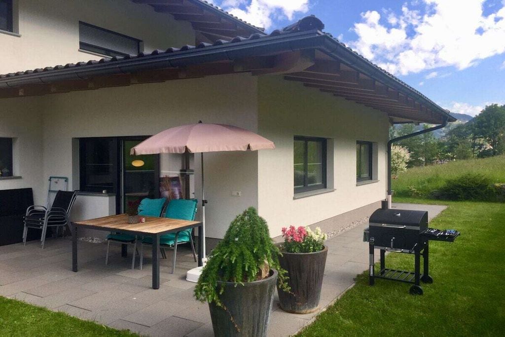 Une terrasse avec une table et des chaises, un barbecue et des plantes en pot.